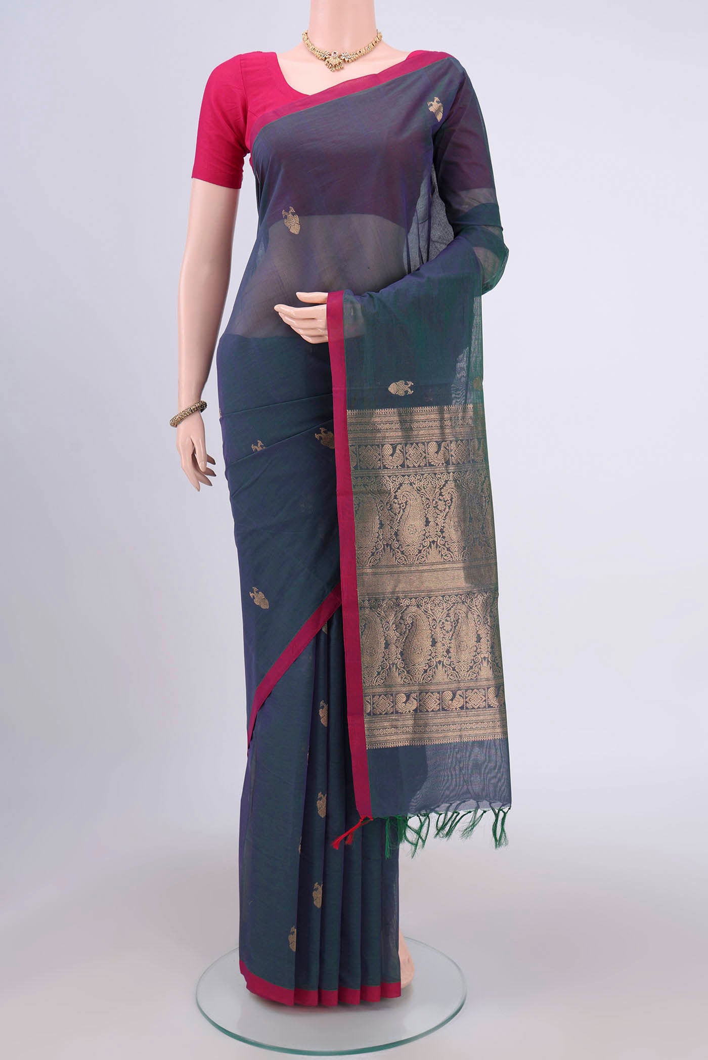 Bottle Green Kanchi Cotton Saree with Zari Butta on the body and Zari Border.  displayed on a mannequin