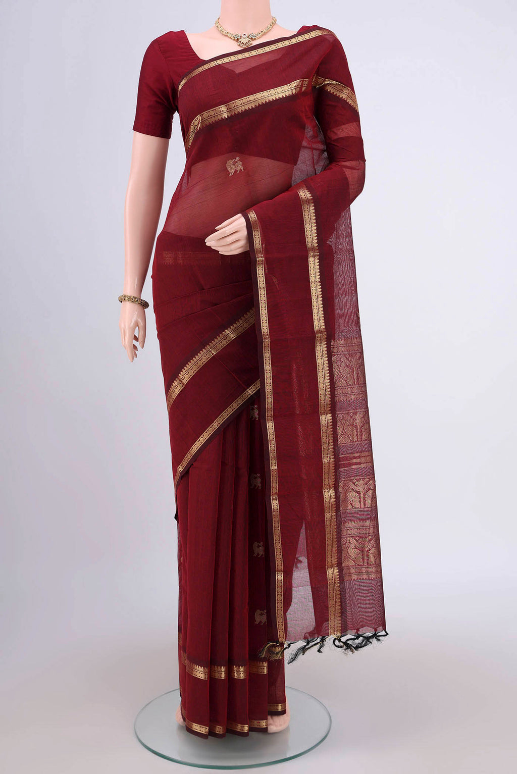 Maroon Kanchi Cotton Saree with Plain Body and Zari Border.  displayed on a mannequin