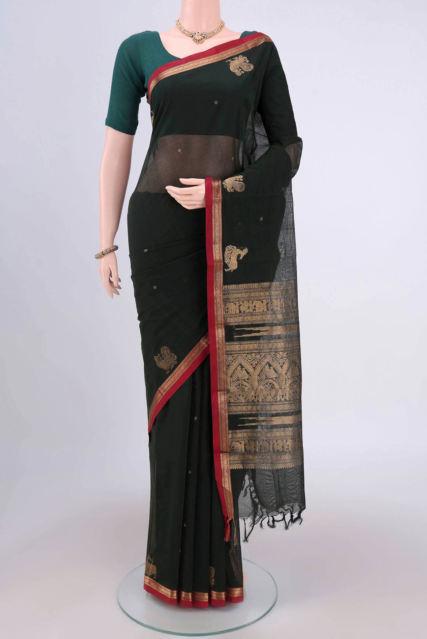 Bottle Green Kanchi Cotton Saree with Zari Butta on the body and Zari Border.  displayed on a mannequin