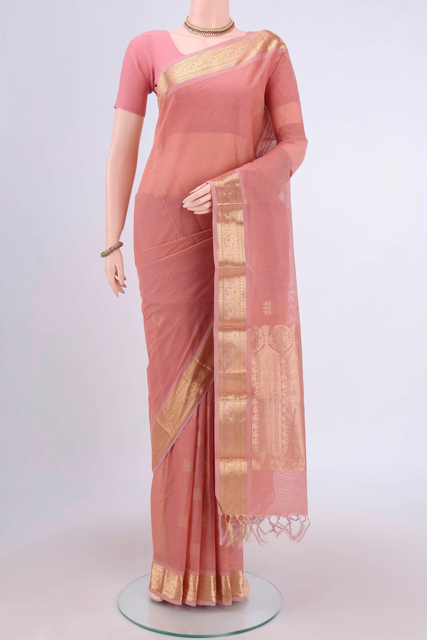 Peach Kanchi Cotton Saree with Zari Butta on the body and Zari Border.  displayed on a mannequin