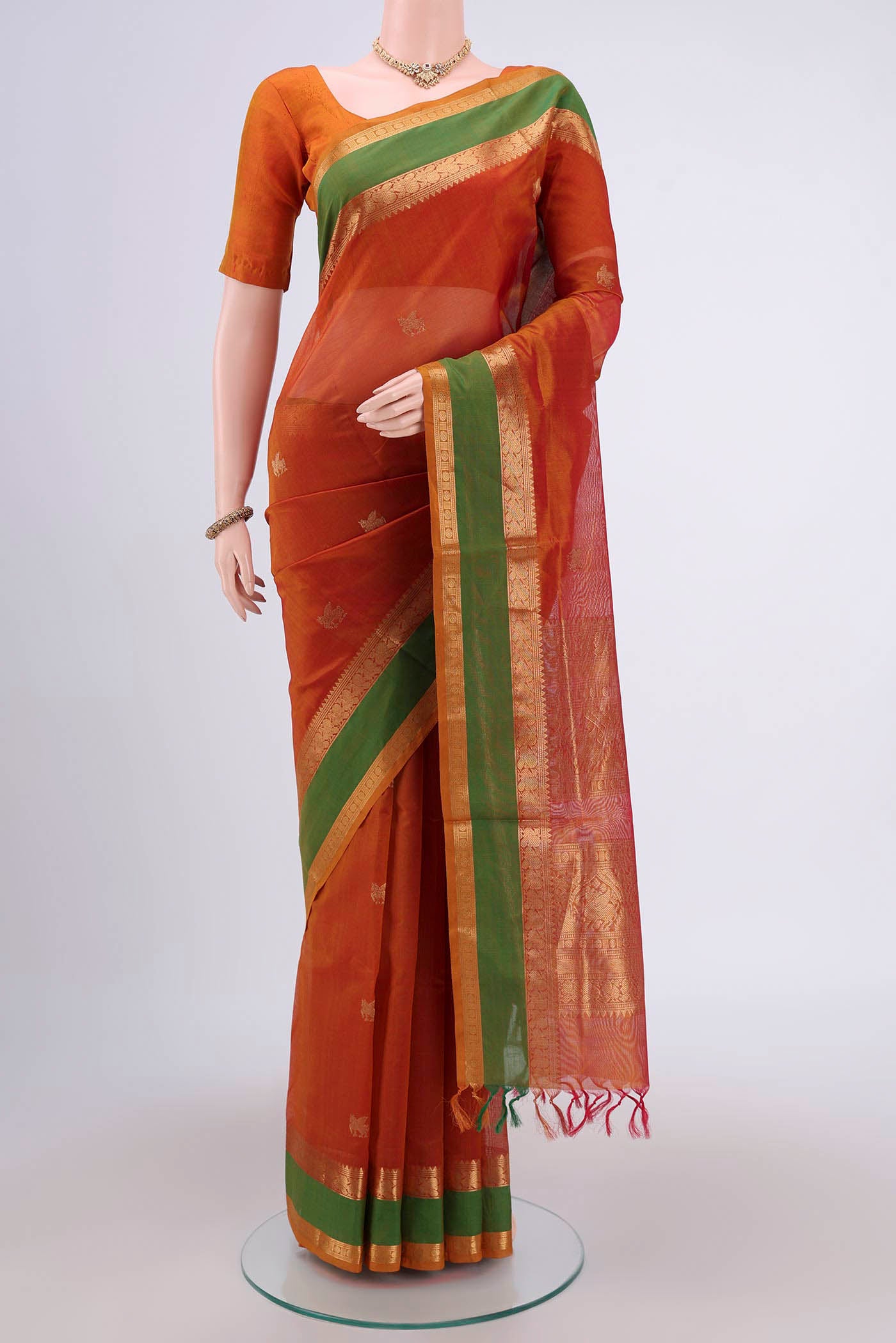 Rust Silk Cotton Saree with Zari Butta on the body and Zari Border.  displayed on a mannequin