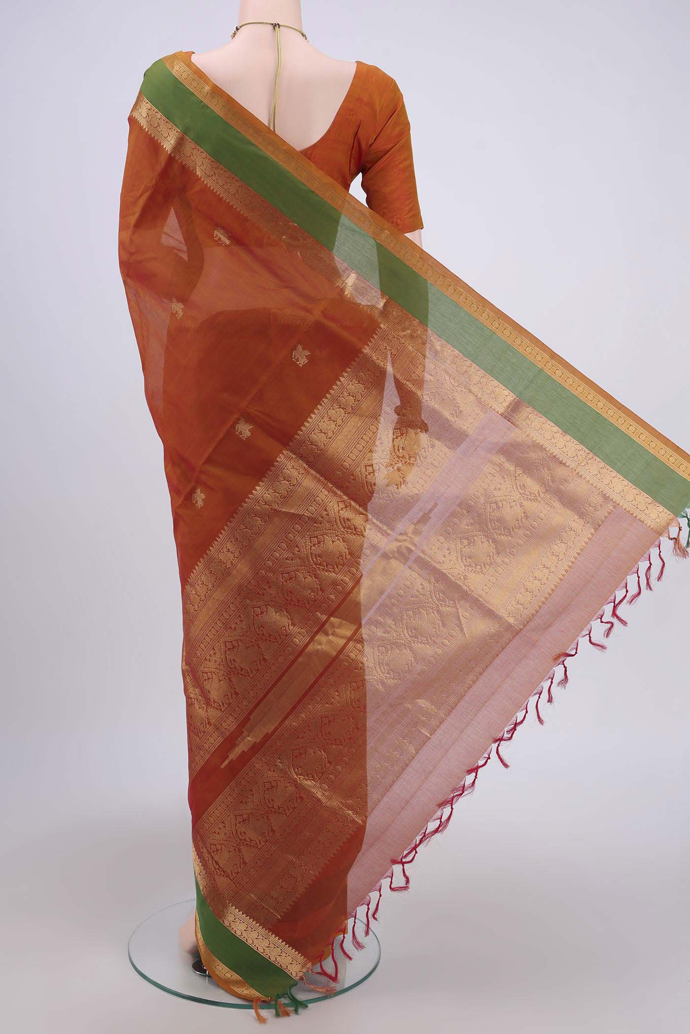 Flat view of Rust Silk Cotton Saree with Zari Butta on the body and Zari Border. 