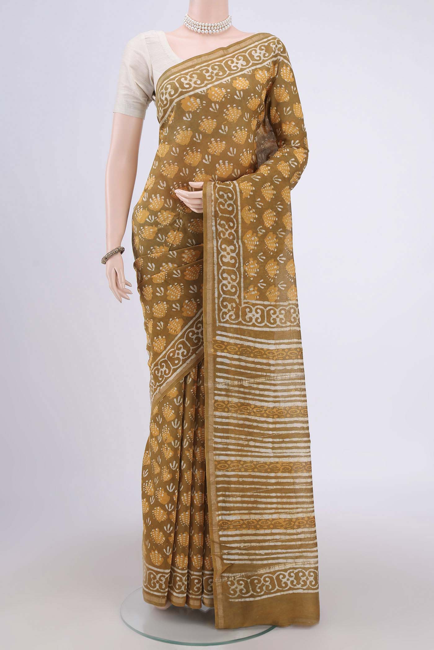 Mustard Maheshwari Silk Cotton Saree with Batik Print on the body and Zari Border.  displayed on a mannequin