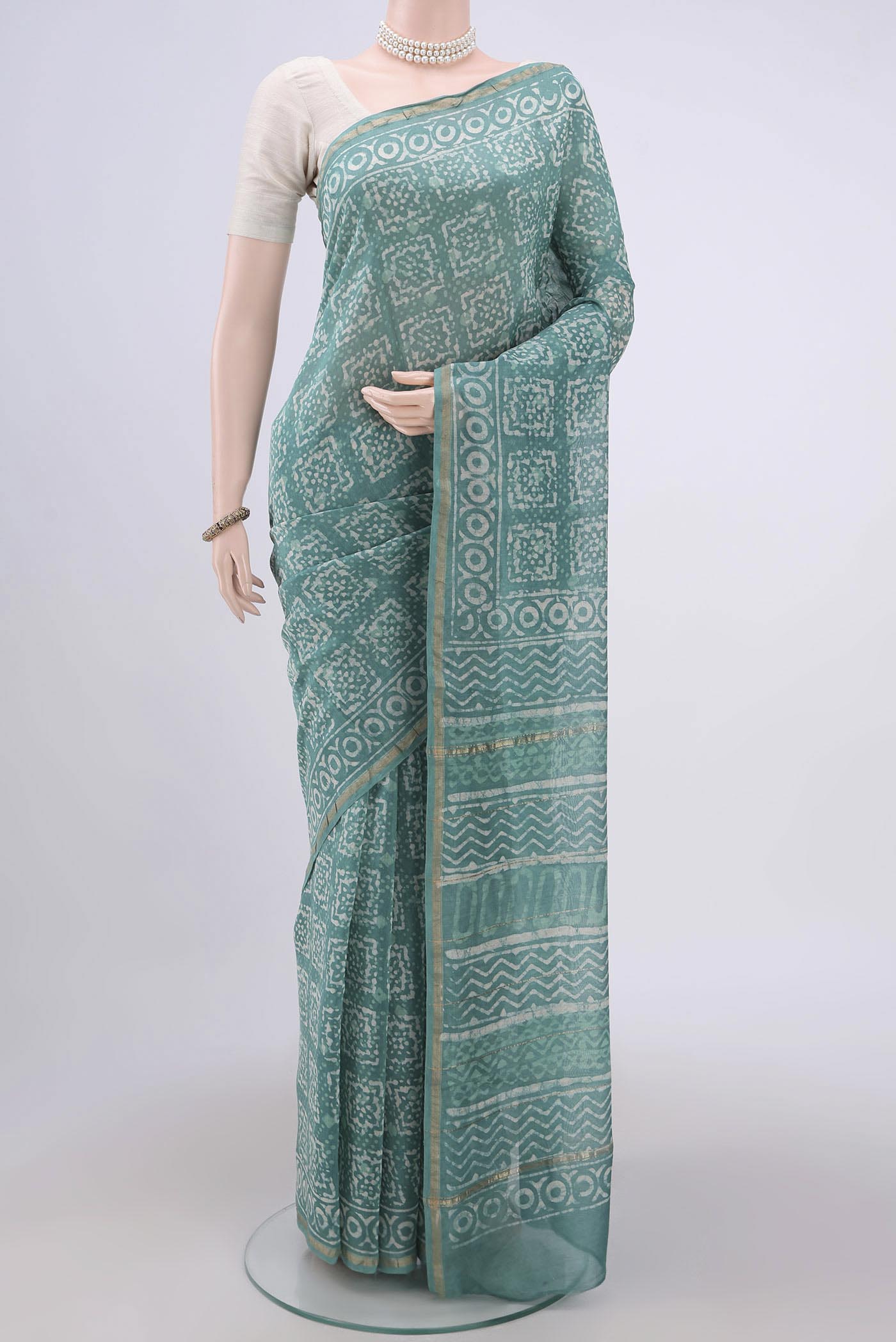 Turquoise Maheshwari Silk Cotton Saree with Batik Print on the body and Zari Border.  displayed on a mannequin