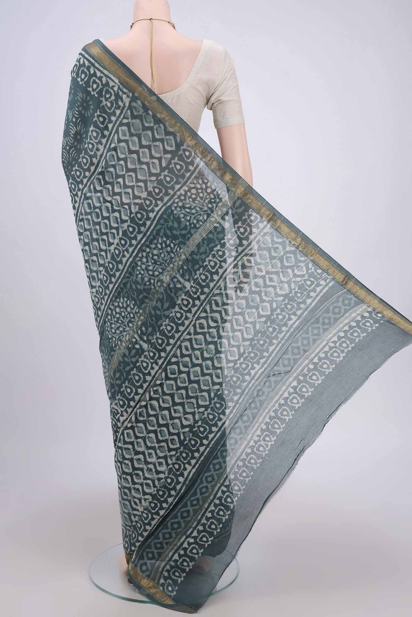 Flat view of Blue Grey Maheshwari Silk Cotton Saree with Batik Print on the body and Zari Border. 