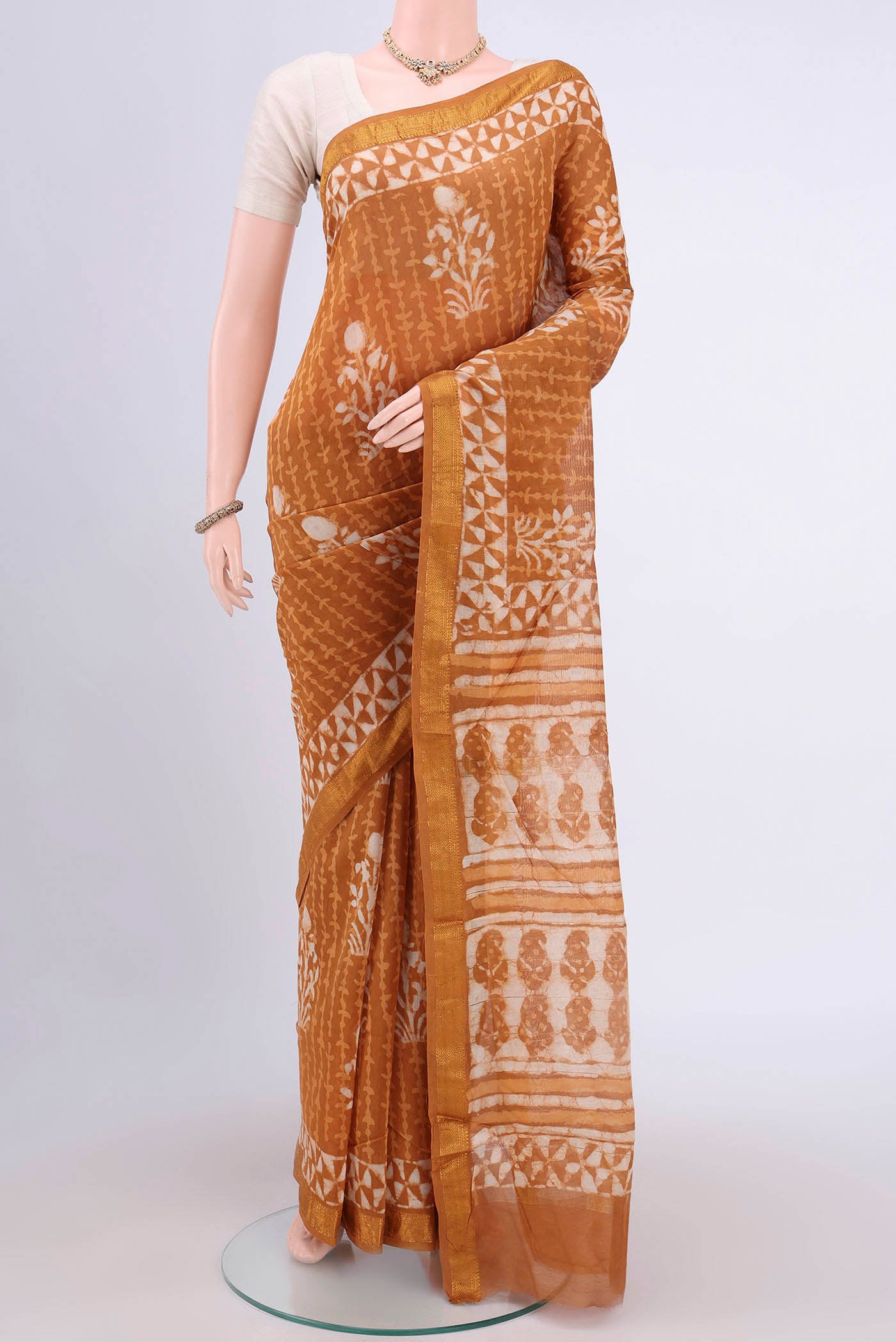 Rust Maheshwari Silk Cotton Saree with Printed design on the body and Zari Border.  displayed on a mannequin