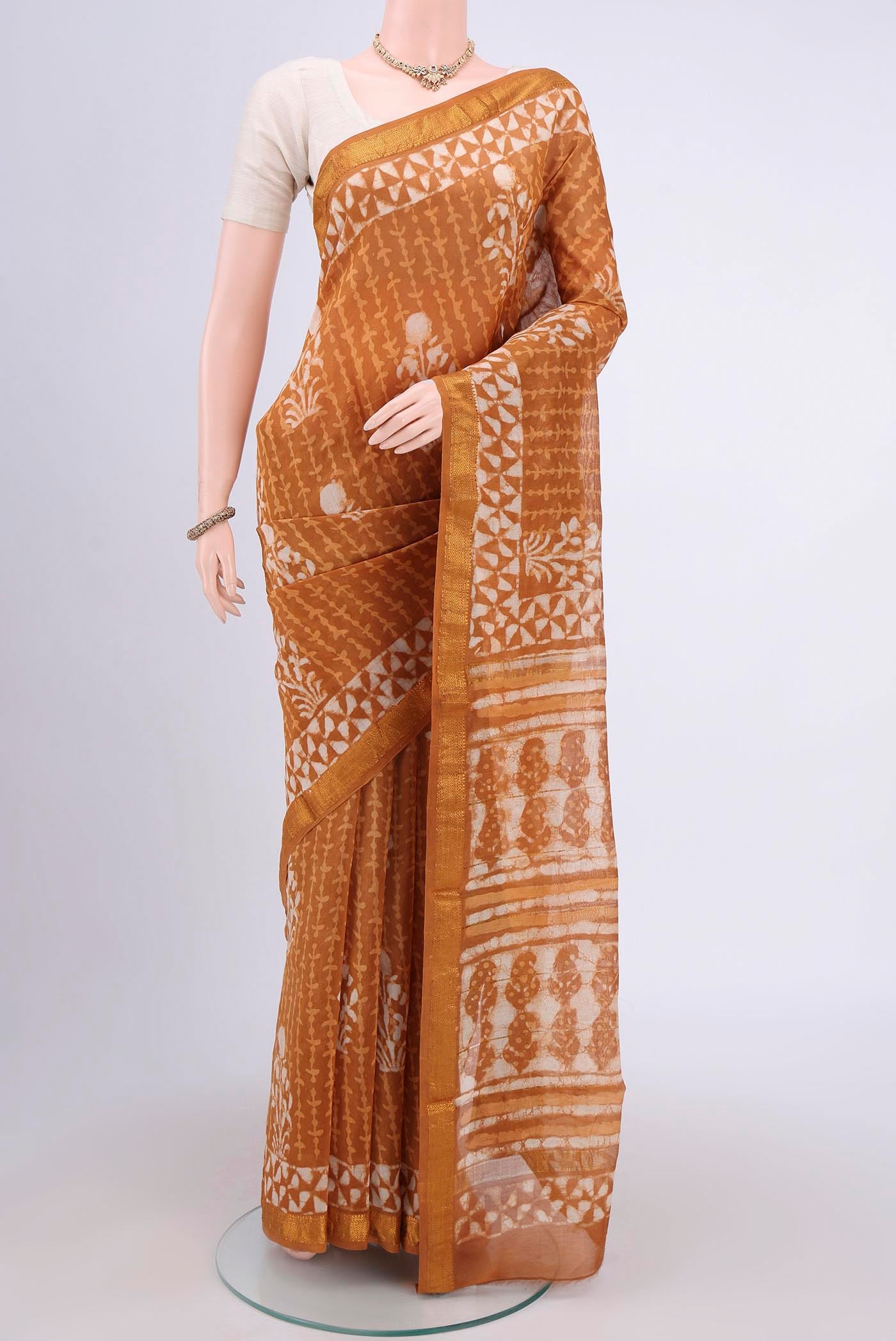 Rust Maheshwari Silk Cotton Saree with Printed design on the body and Zari Border.  displayed on a mannequin