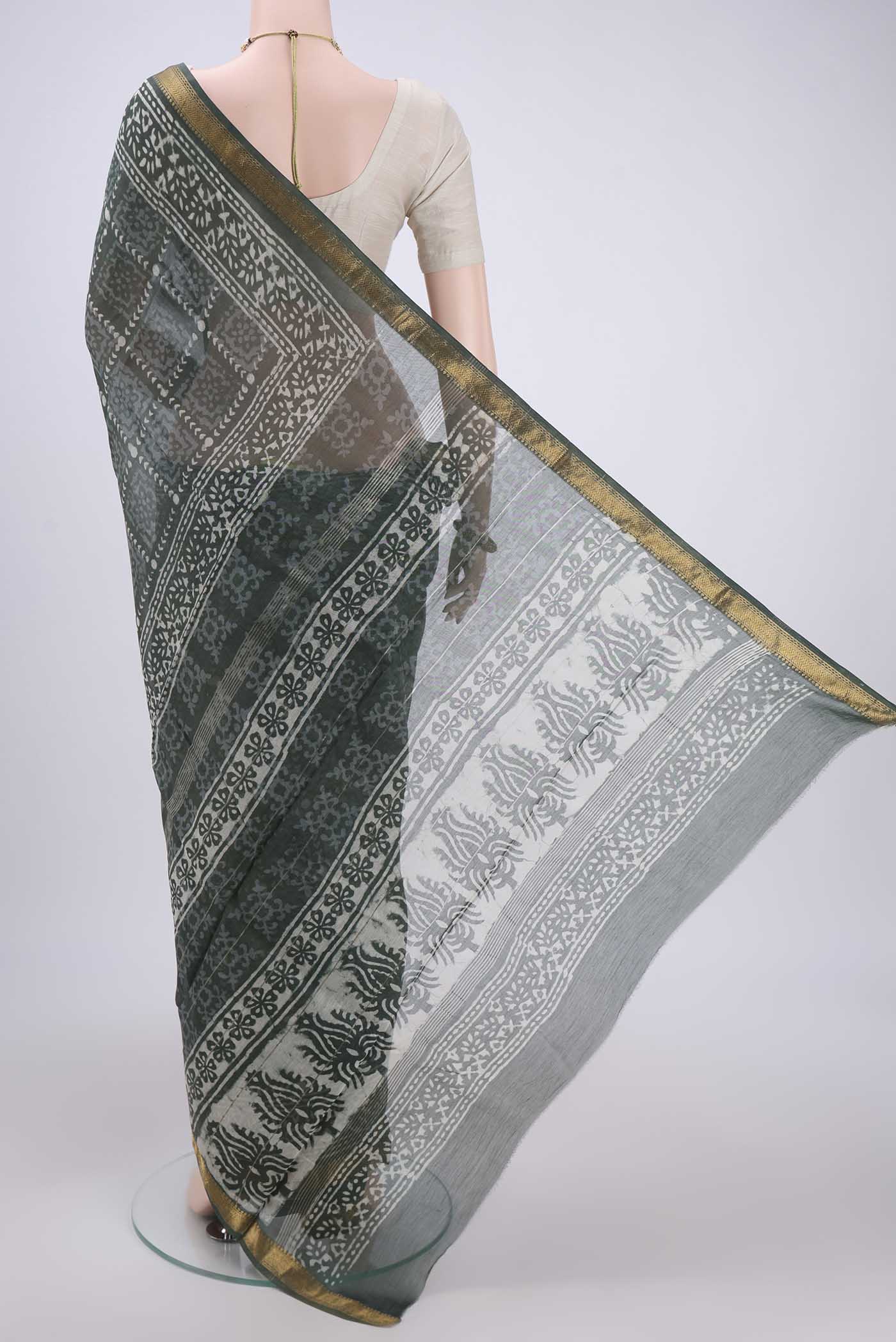 Flat view of Olive Green Maheshwari Silk Cotton Saree with Batik Print on the body and Zari Border. 