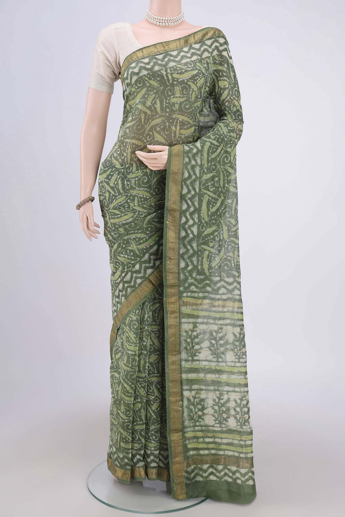 Olive Green Maheshwari Silk Cotton Saree with Batik Print on the body and Zari Border.  displayed on a mannequin