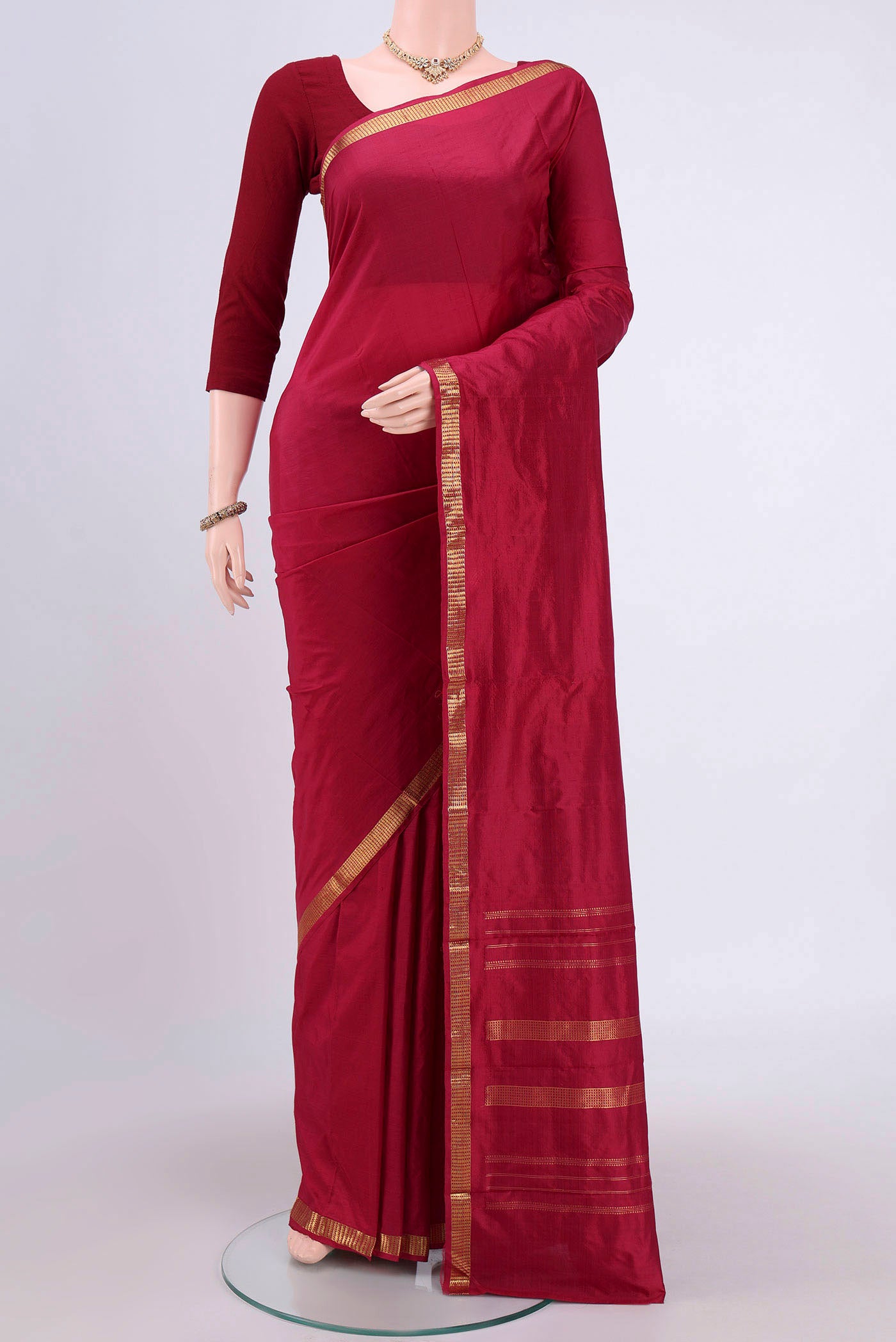 Maroon Kanchipuram Silk Saree with Plain Body and Zari Border.  displayed on a mannequin
