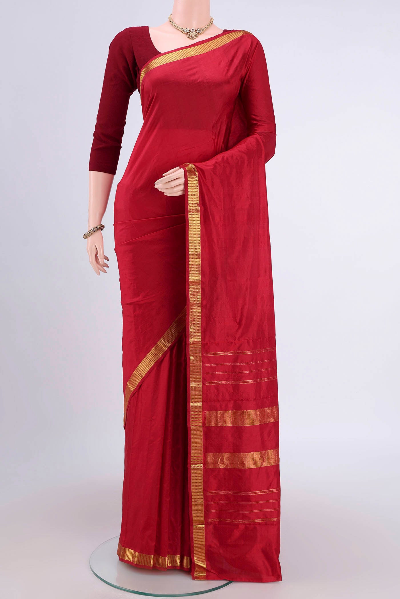 Maroon Kanchipuram Saree with Plain Body and Zari Border.  displayed on a mannequin