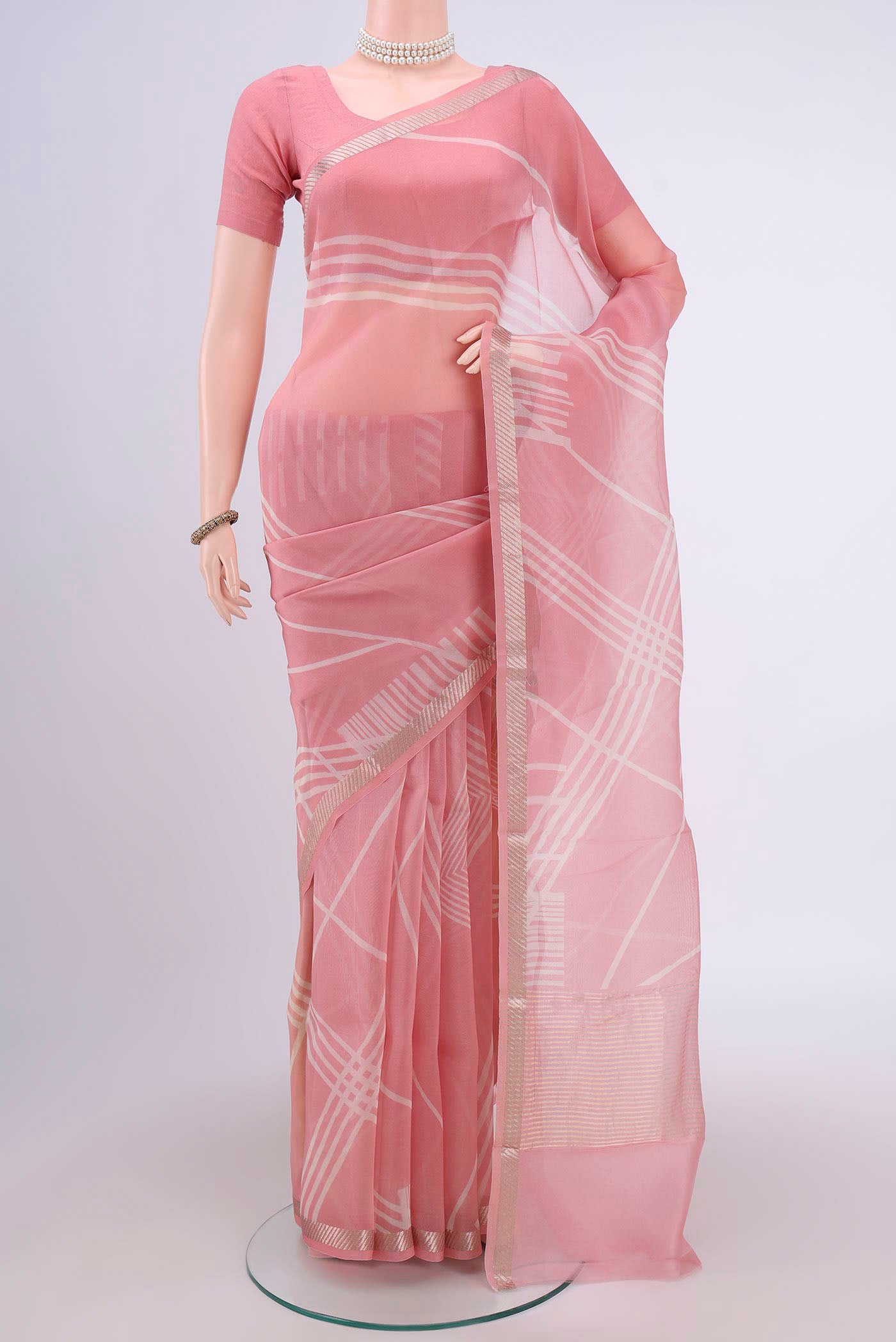 Peach Organza Silk Saree with Floral Print on the body and Zari Border.  displayed on a mannequin