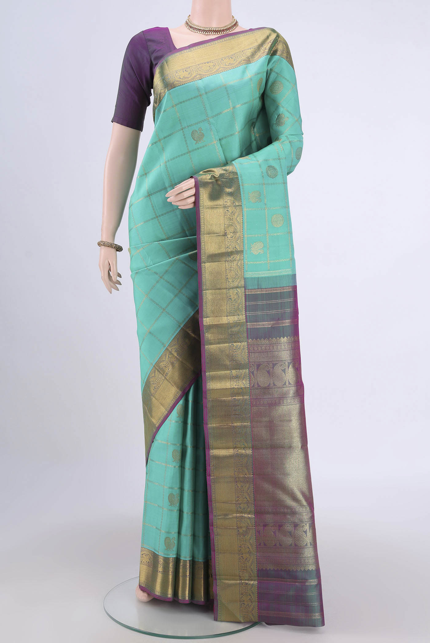 Turquoise Kanjivaram Saree with Zari Butta on the body and Zari Border.  displayed on a mannequin