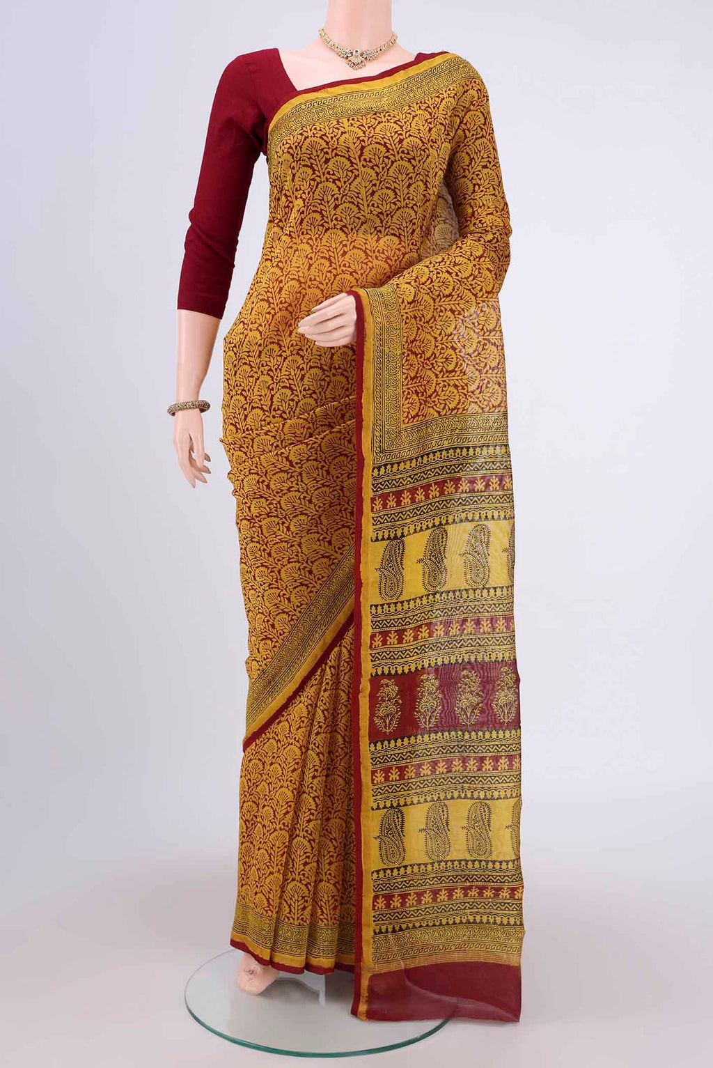Mustard Maheshwari Silk Cotton Saree with Printed design on the body and Zari Border.  displayed on a mannequin