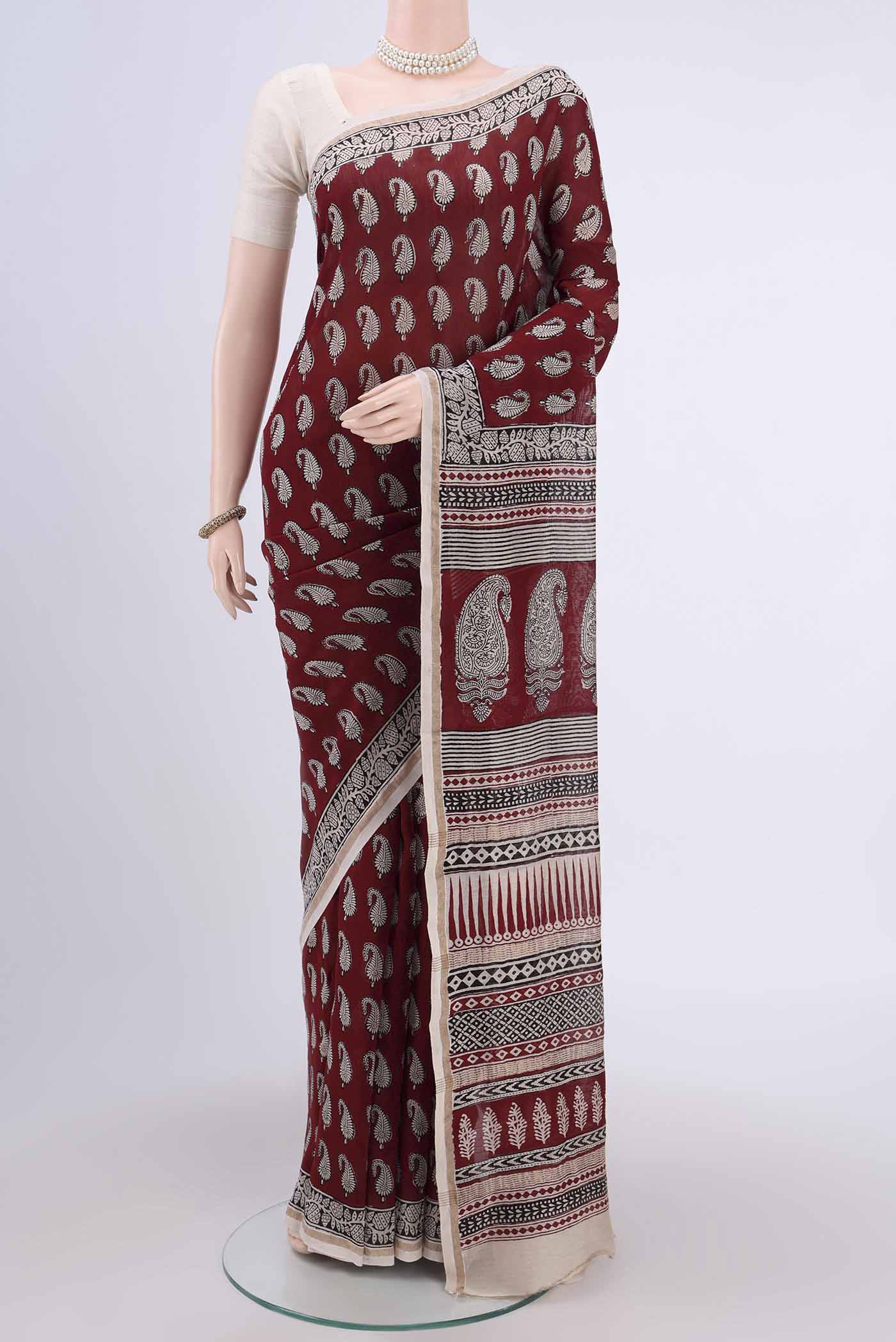 Maroon Maheshwari Silk Cotton Saree with Printed design on the body and Zari Border.  displayed on a mannequin