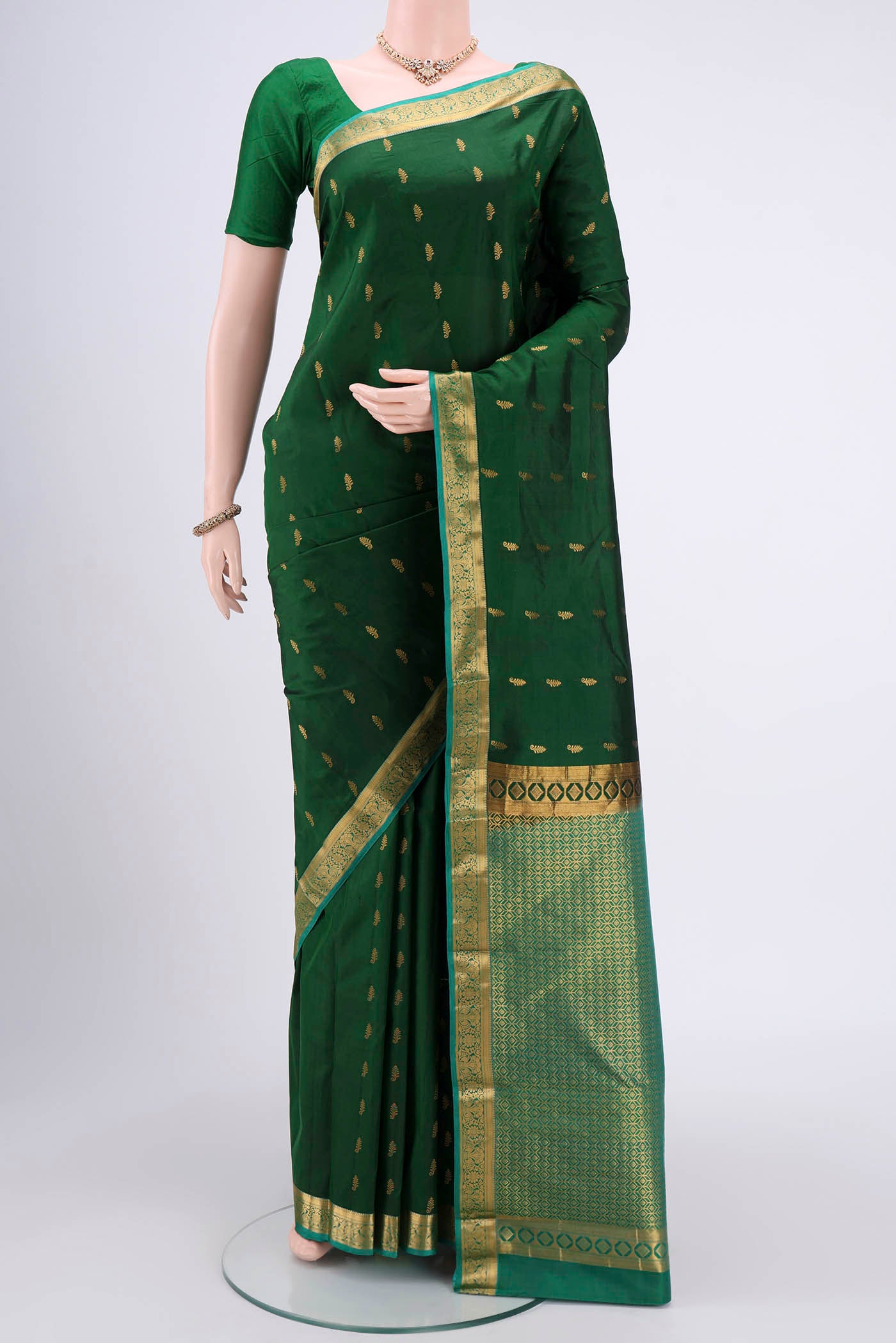 Bottle Green Kanjivaram Silk Saree with Zari Butta on the body and Zari Border.  displayed on a mannequin