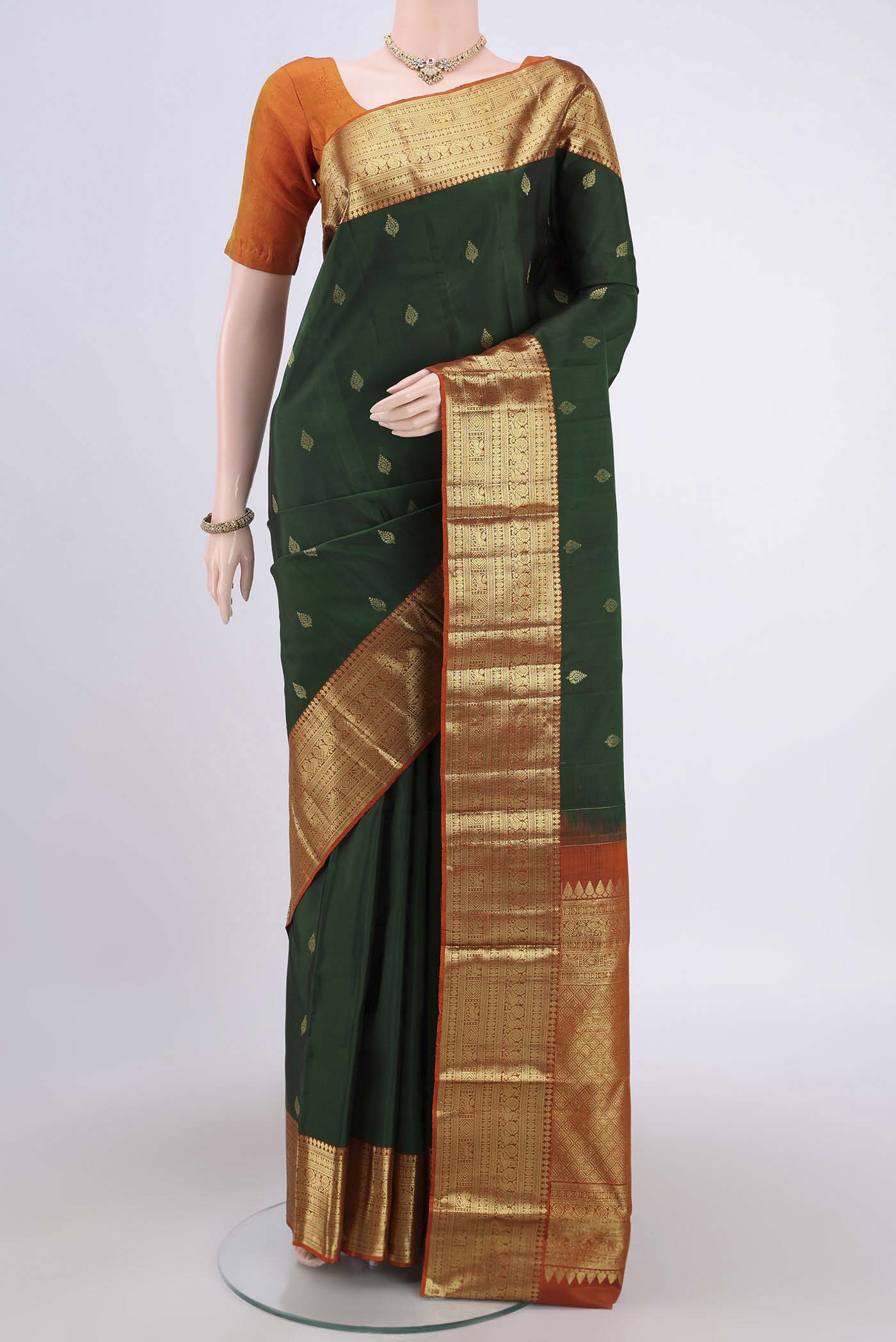 Bottle Green Kanchipuram Saree with Zari Butta on the body and Zari Border.  displayed on a mannequin