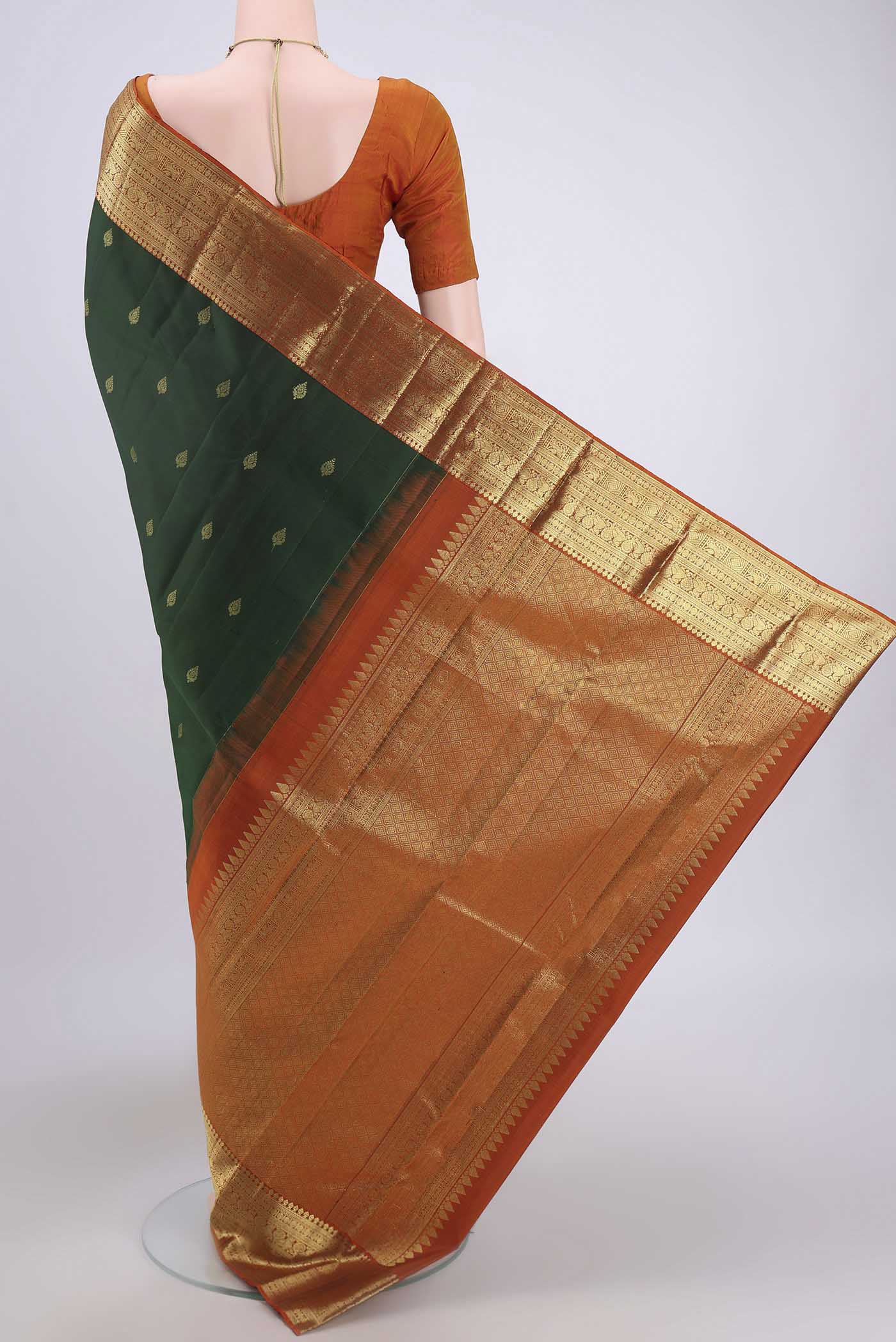 Flat view of Bottle Green Kanchipuram Saree with Zari Butta on the body and Zari Border. 
