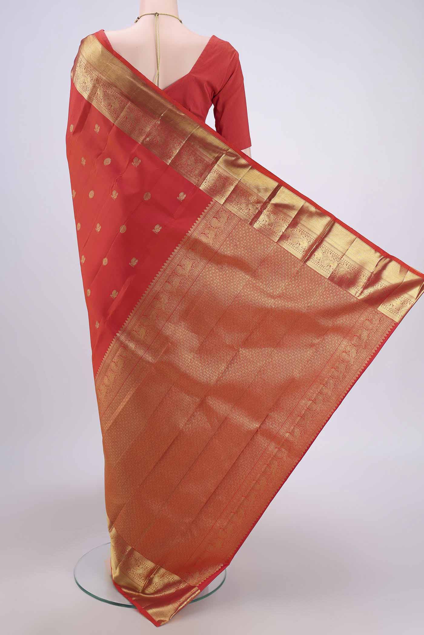 Flat view of Orange Kanchipuram Silk Saree with Zari Butta on the body and Zari Border. 