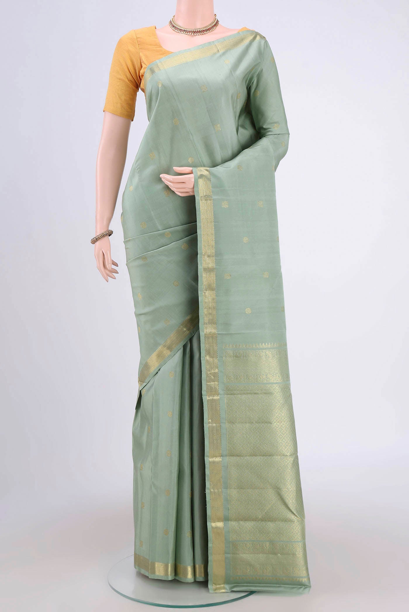 Sage Green Kanchipuram Saree with Zari Butta on the body and Zari Border.  displayed on a mannequin
