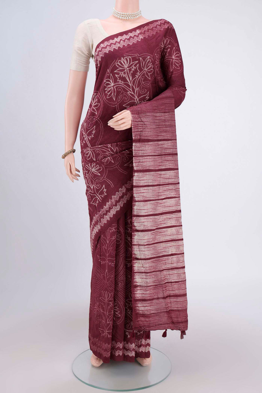 Maroon Printed Silk Saree with Printed design on the body and Plain Border.  displayed on a mannequin