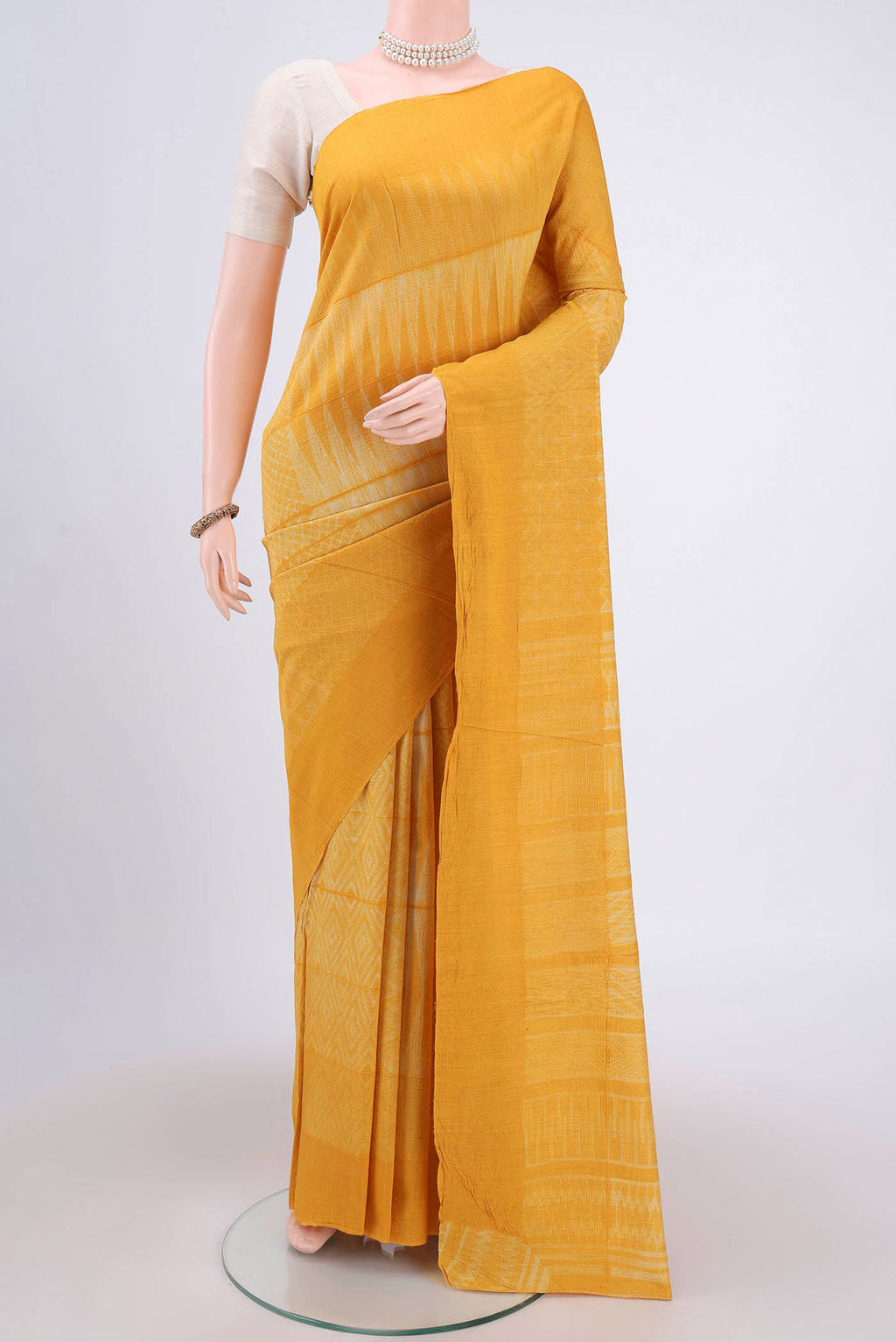 Mustard Printed Silk Saree with Printed design on the body and Plain Border.  displayed on a mannequin