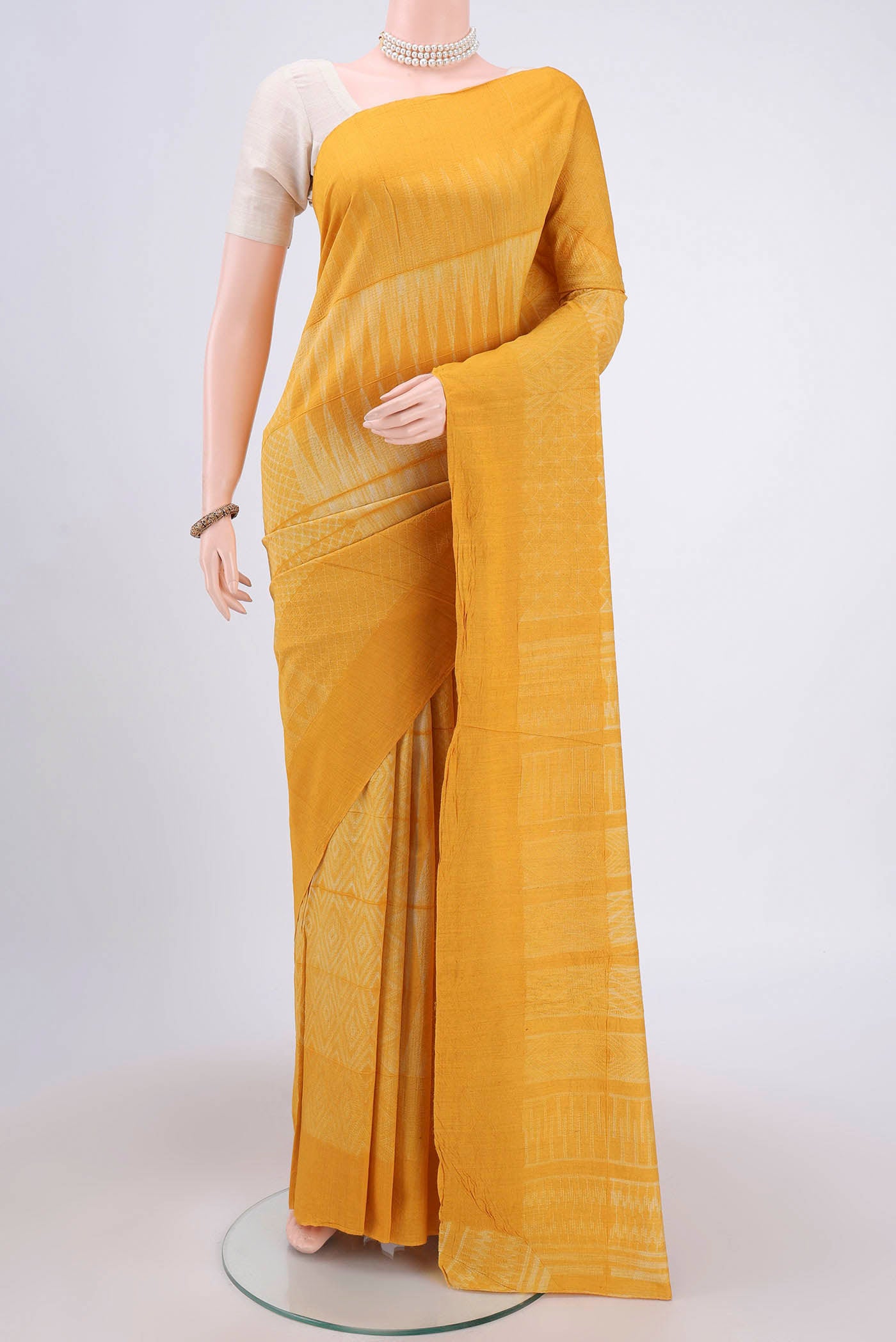 Mustard Printed Silk Saree with Printed design on the body and Plain Border.  displayed on a mannequin