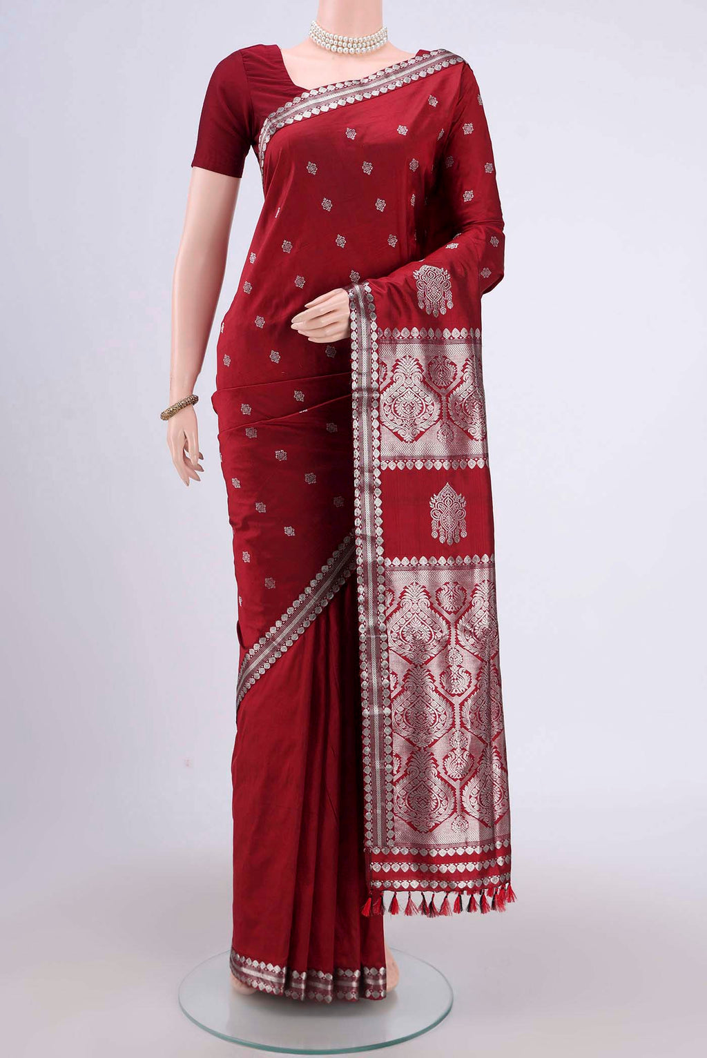 Maroon Assam Silk Saree with Zari Butta on the body and Zari Border.  displayed on a mannequin