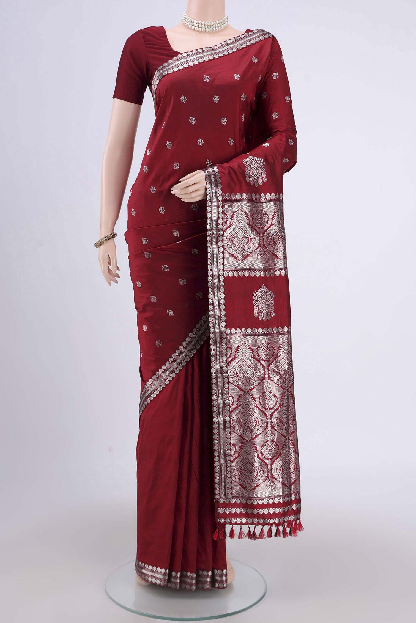 Maroon Assam Silk Saree with Zari Butta on the body and Zari Border.  displayed on a mannequin