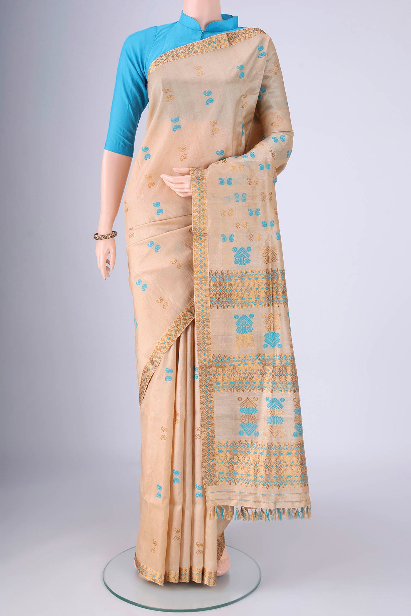 Beige Assam Silk Saree with Thread Butta on the body and Thread Border.  displayed on a mannequin