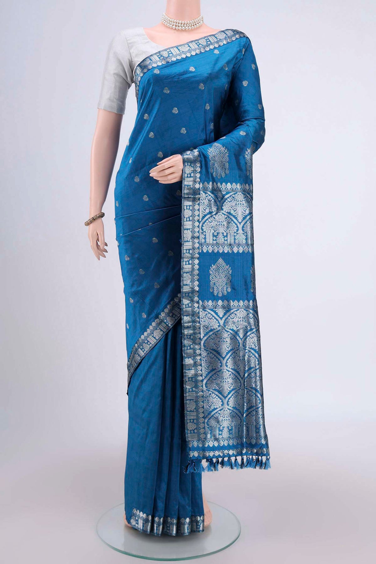 Turquoise Assam Silk Saree with Zari Butta on the body and Zari Border.  displayed on a mannequin