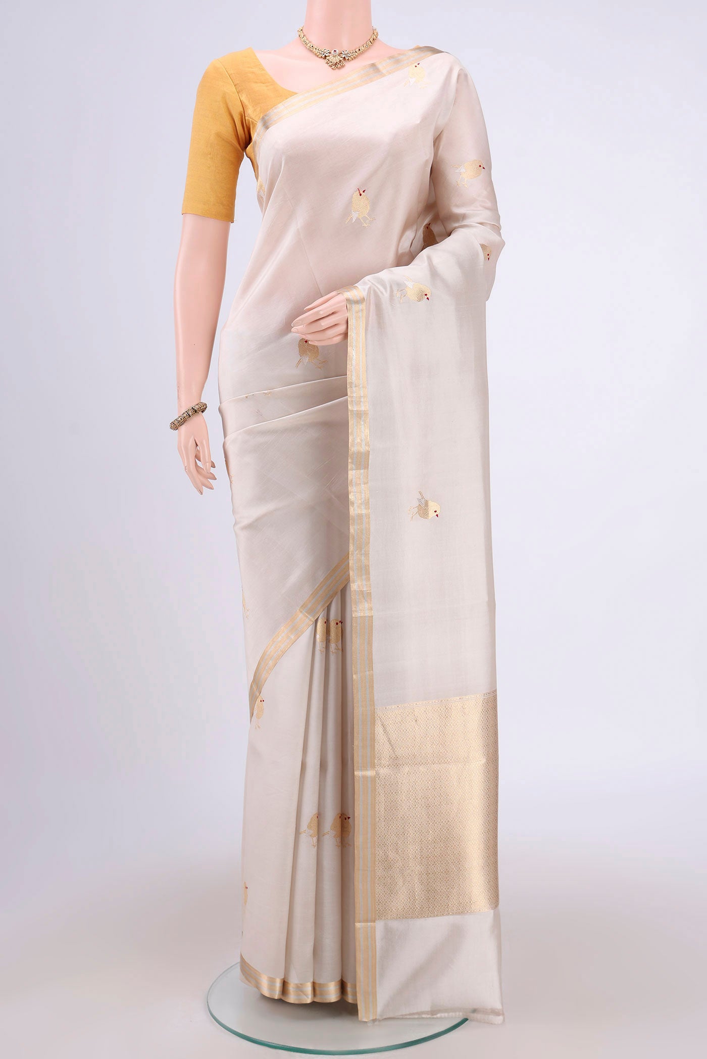 Cream Banarasi Katan Silk Saree with Zari Butta on the body and Zari Border.  displayed on a mannequin