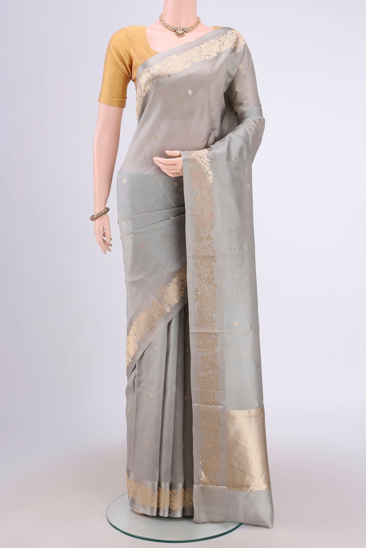 Grey Banarasi Katan Silk Saree with Zari Butta on the body and Zari Border.  displayed on a mannequin