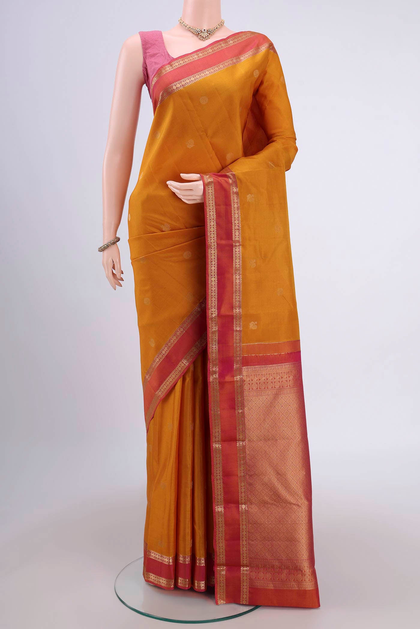 Mustard Kanchipuram Saree with Zari Butta on the body and Zari Border.  displayed on a mannequin
