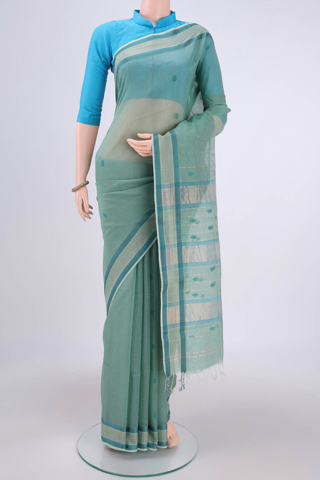 Sage Green Maheshwari Silk Cotton Saree with Thread Butta on the body and Zari And Thread Border.  displayed on a mannequin