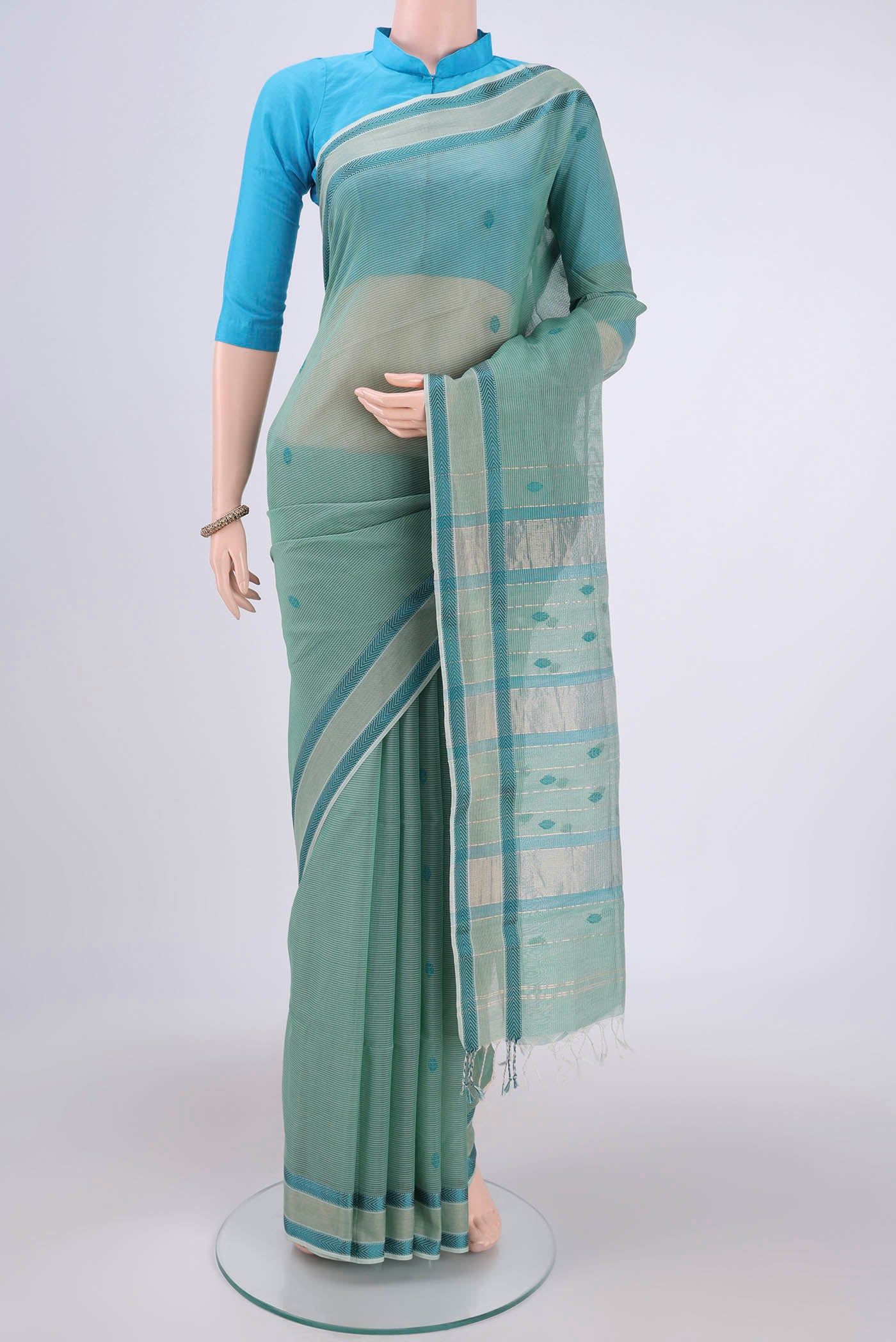 Sage Green Maheshwari Silk Cotton Saree with Thread Butta on the body and Zari And Thread Border.  displayed on a mannequin