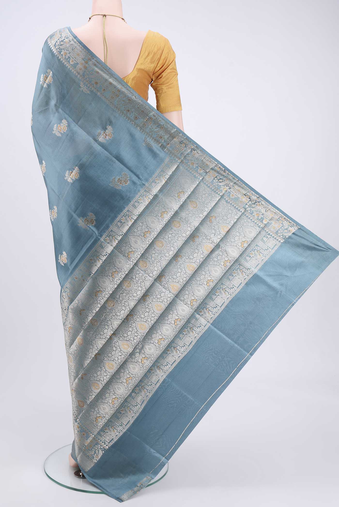 Flat view of Blue Grey Banarasi Raw Silk Saree with Zari Butta on the body and Zari Border. 