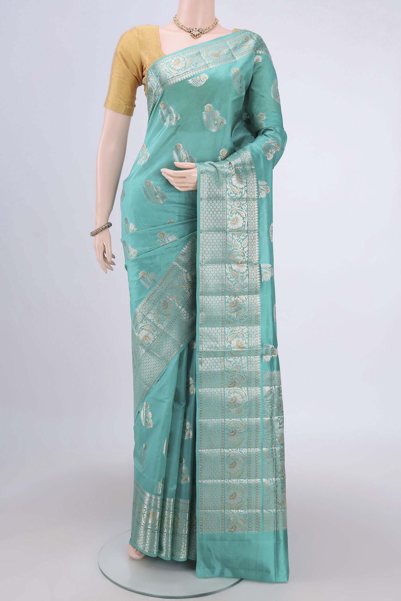 Turquoise Banarasi Raw Silk Saree with Zari Butta on the body and Zari Border.  displayed on a mannequin