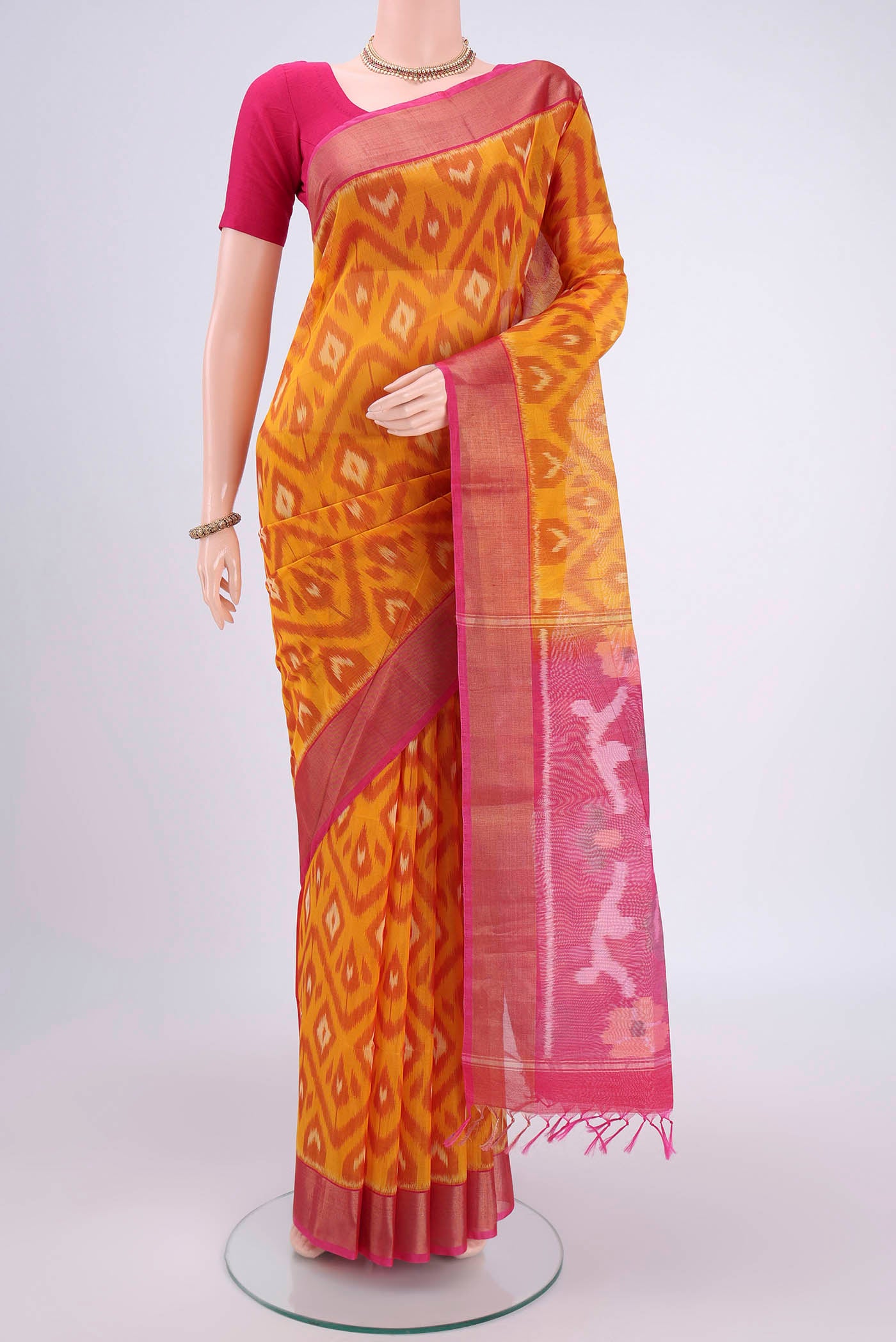 Mustard Silk Cotton Saree with Ikat design on the body and Zari Border.  displayed on a mannequin