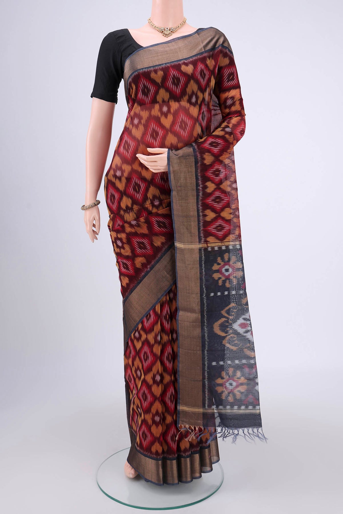 Maroon Silk Cotton Saree with Ikat design on the body and Zari Border.  displayed on a mannequin