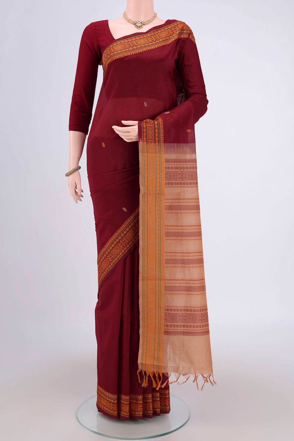 Maroon Blended Poly Cotton Saree with Thread Butta on the body and Thread Border.  displayed on a mannequin