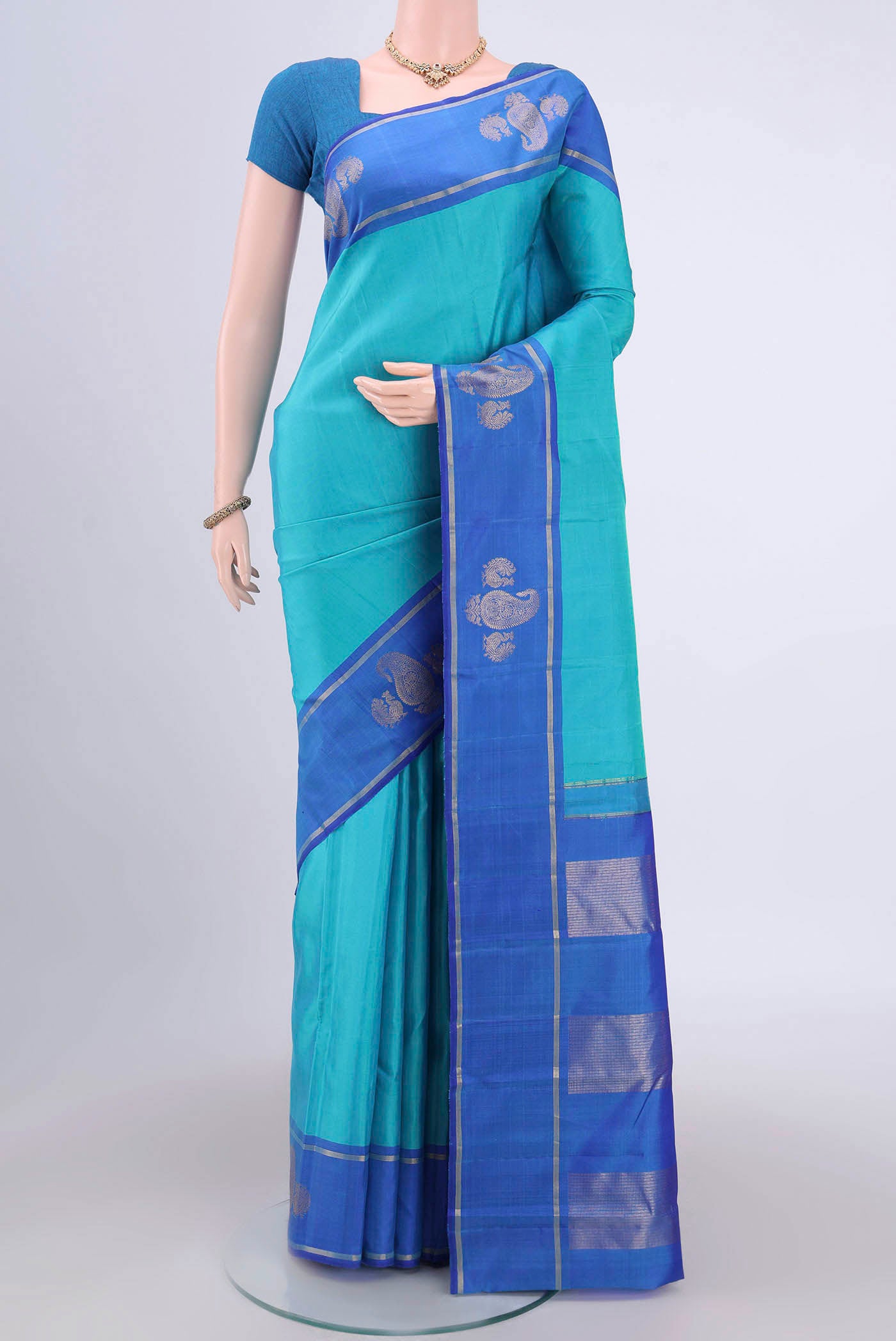 Turquoise Kanchipuram Silk Saree with Plain Body and Zari Border.  displayed on a mannequin