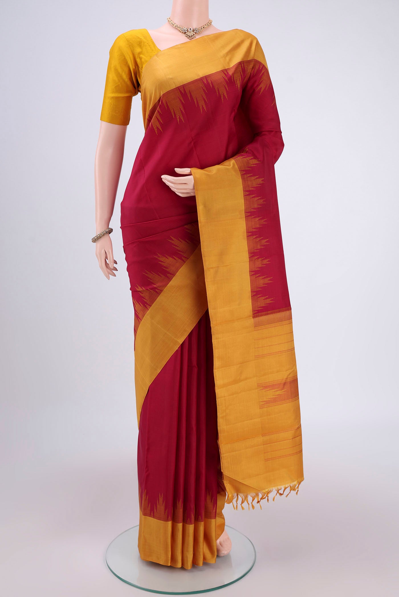 Maroon Kanjivaram Saree with Plain Body and Zari Border.  displayed on a mannequin