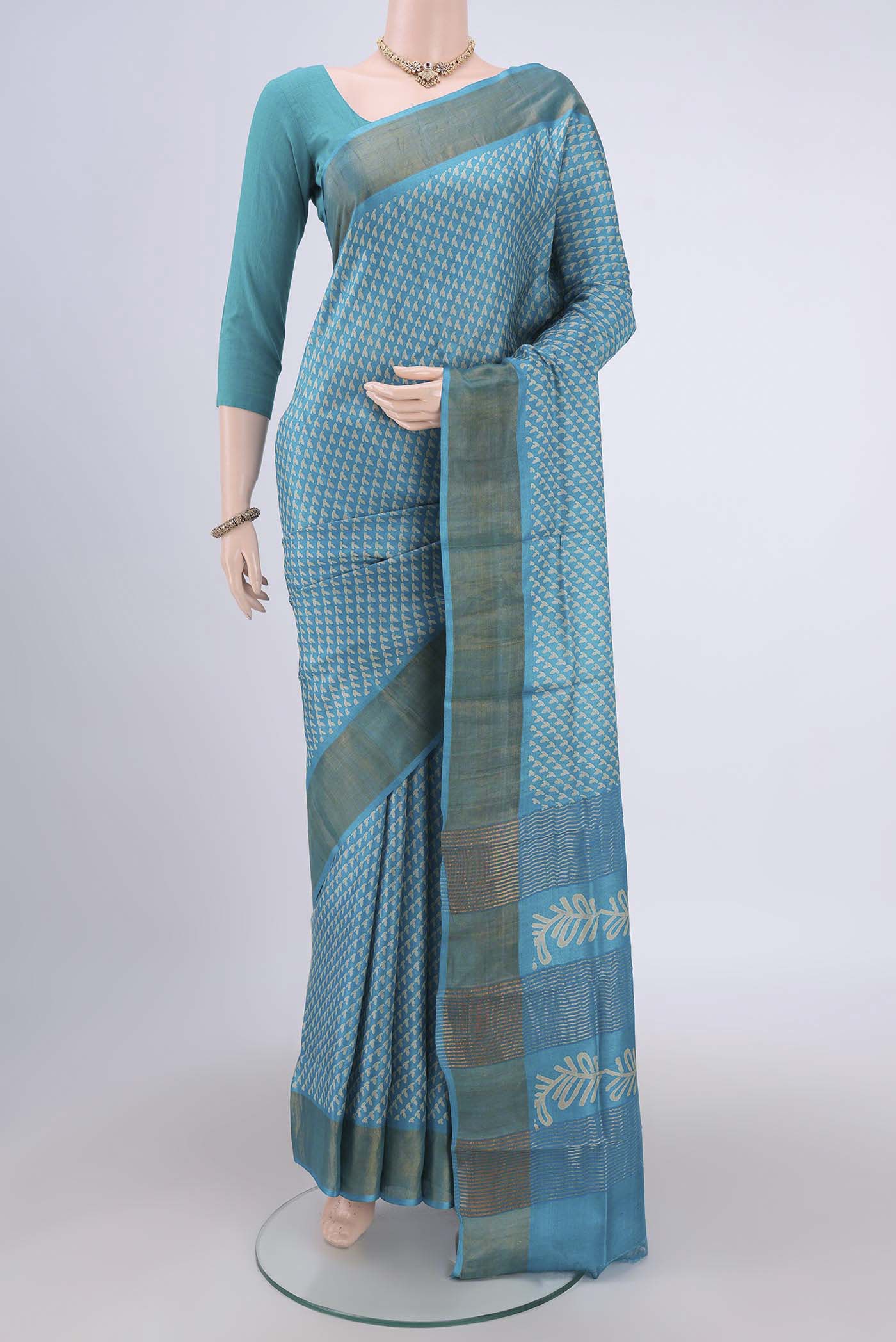 Turquoise Tussar Silk Saree with Printed design on the body and Zari Border.  displayed on a mannequin