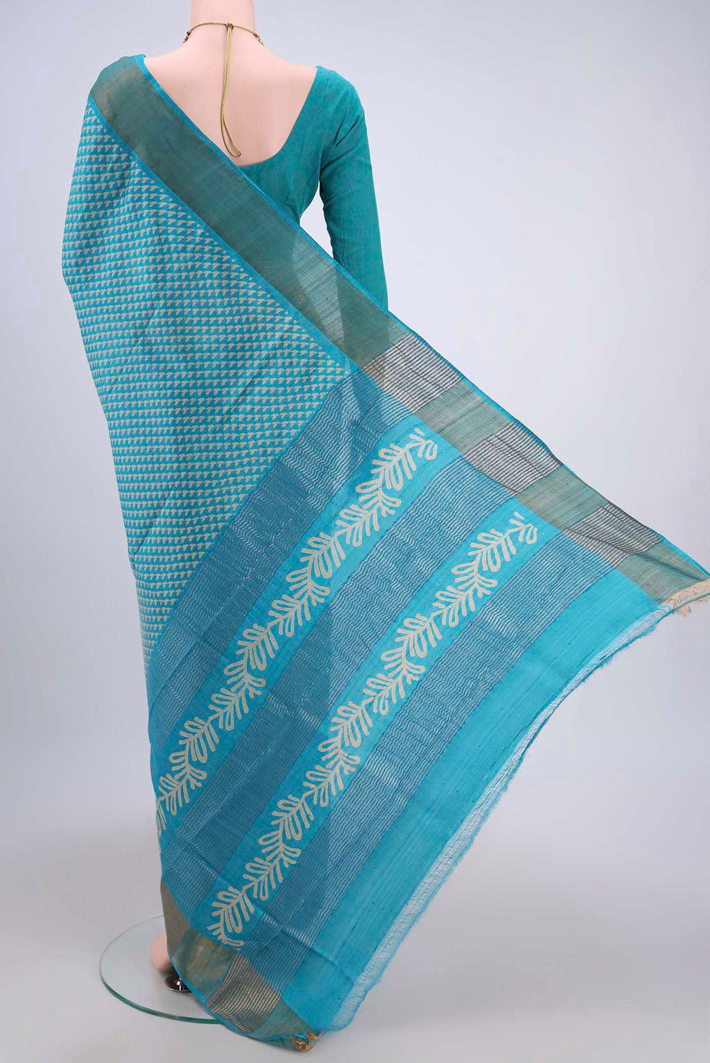 Flat view of Turquoise Tussar Silk Saree with Printed design on the body and Zari Border. 