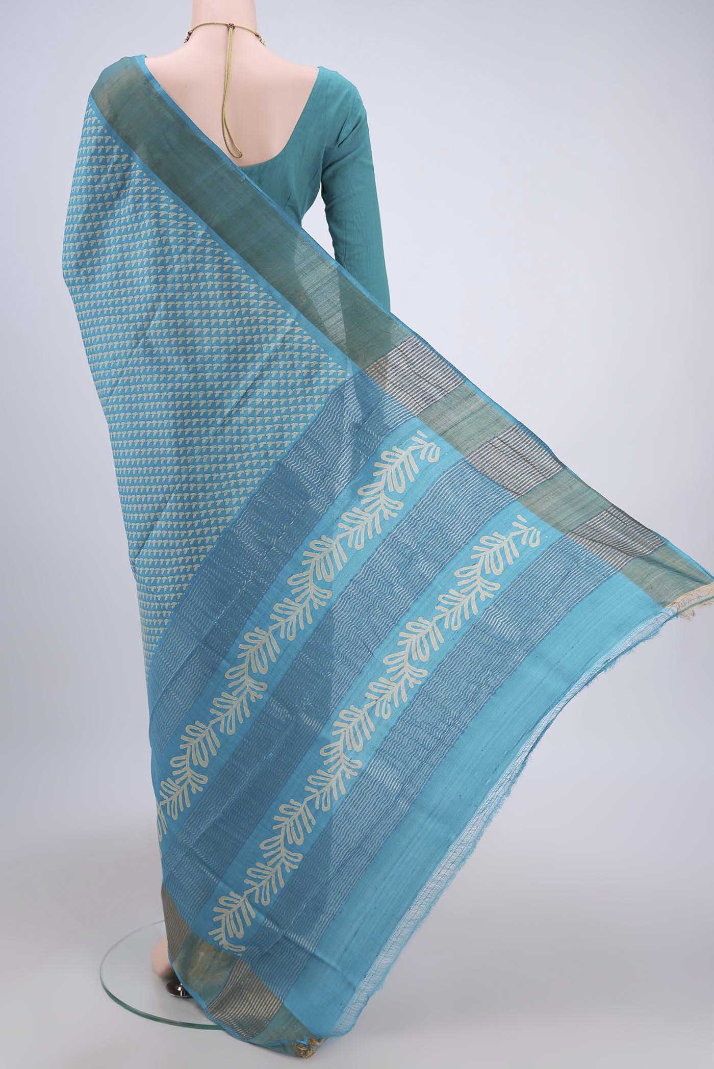 Flat view of Turquoise Tussar Silk Saree with Printed design on the body and Zari Border. 