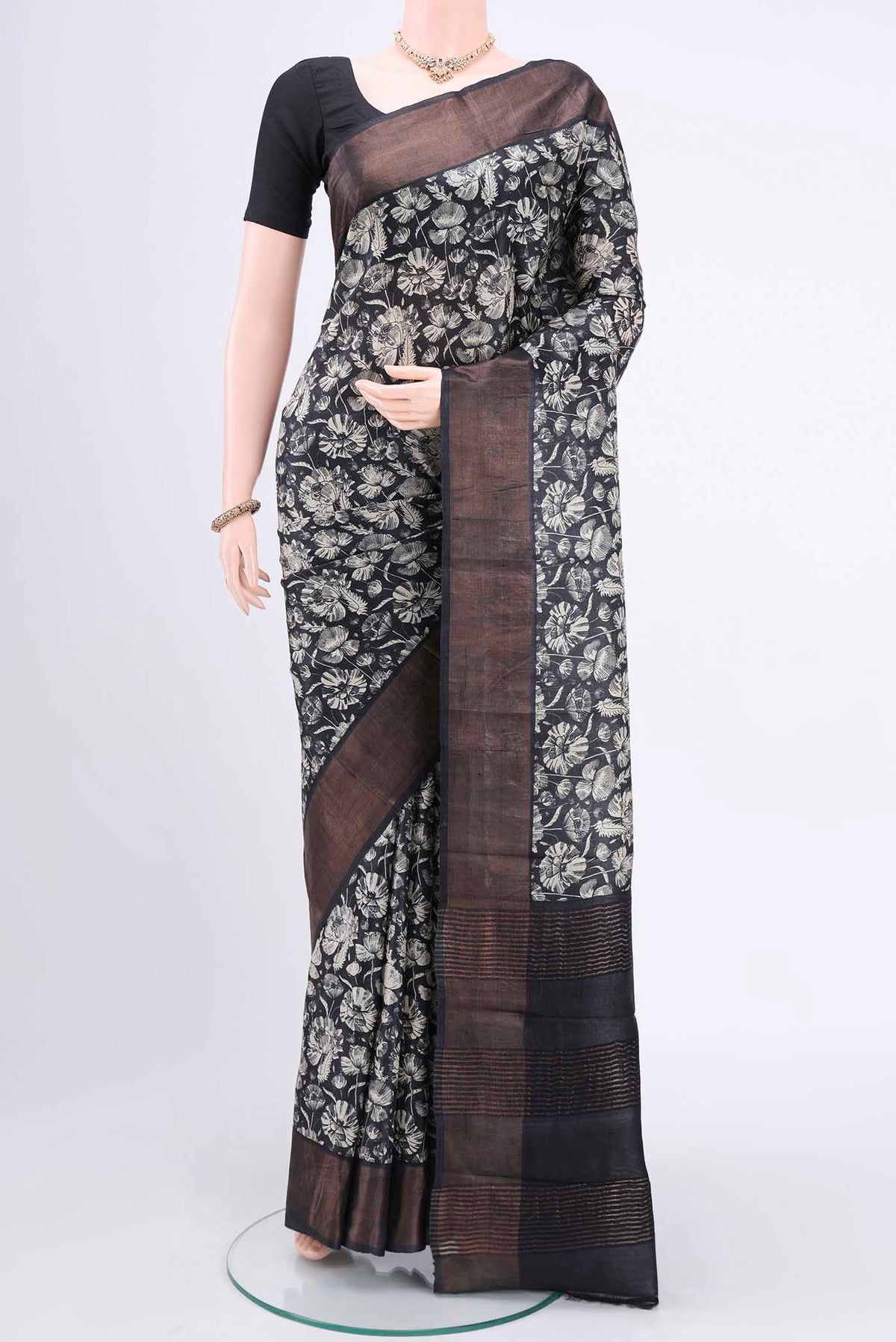 Black Printed Silk Saree with Floral Print on the body and Zari Border.  displayed on a mannequin