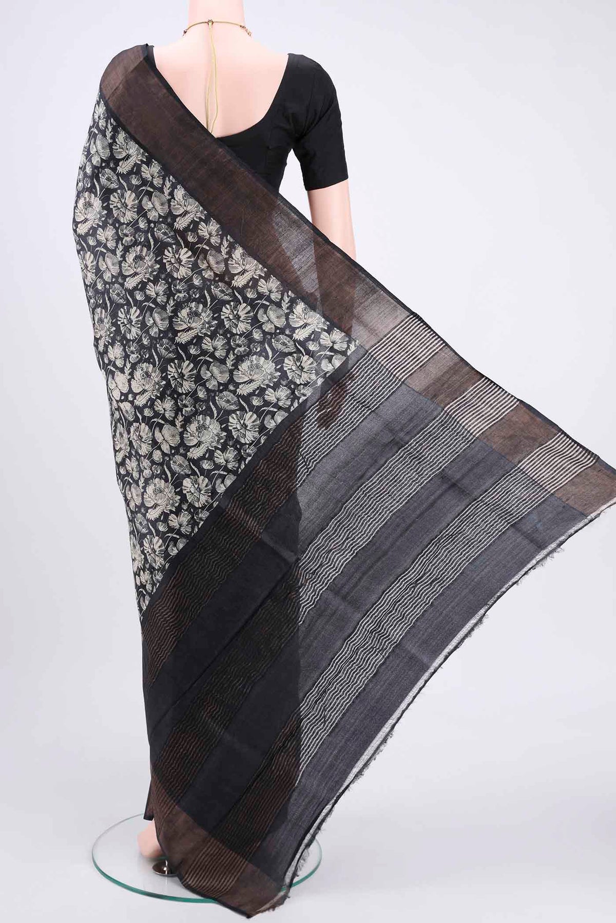 Flat view of Black Printed Silk Saree with Floral Print on the body and Zari Border. 