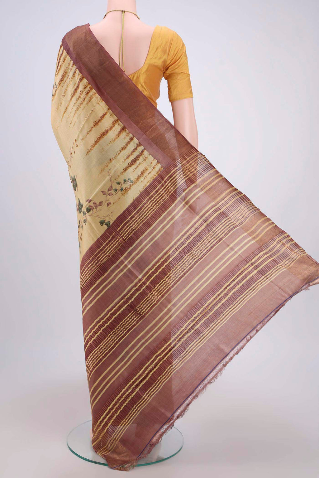 Flat view of Cream Tussar Silk Saree with Printed design on the body and Zari Border. 