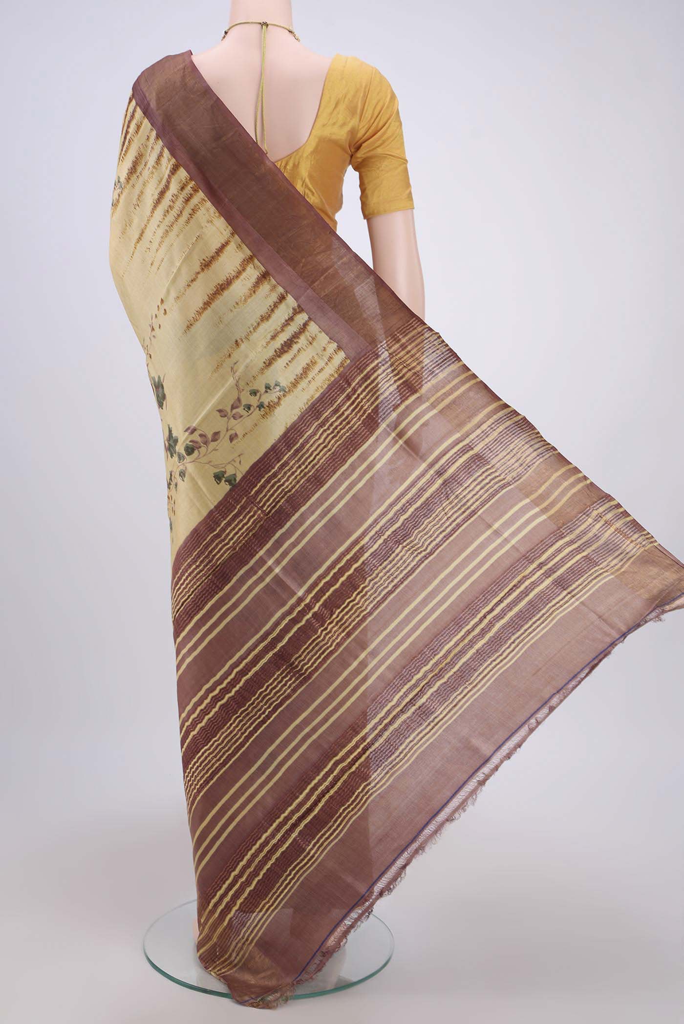 Flat view of Cream Tussar Silk Saree with Printed design on the body and Zari Border. 
